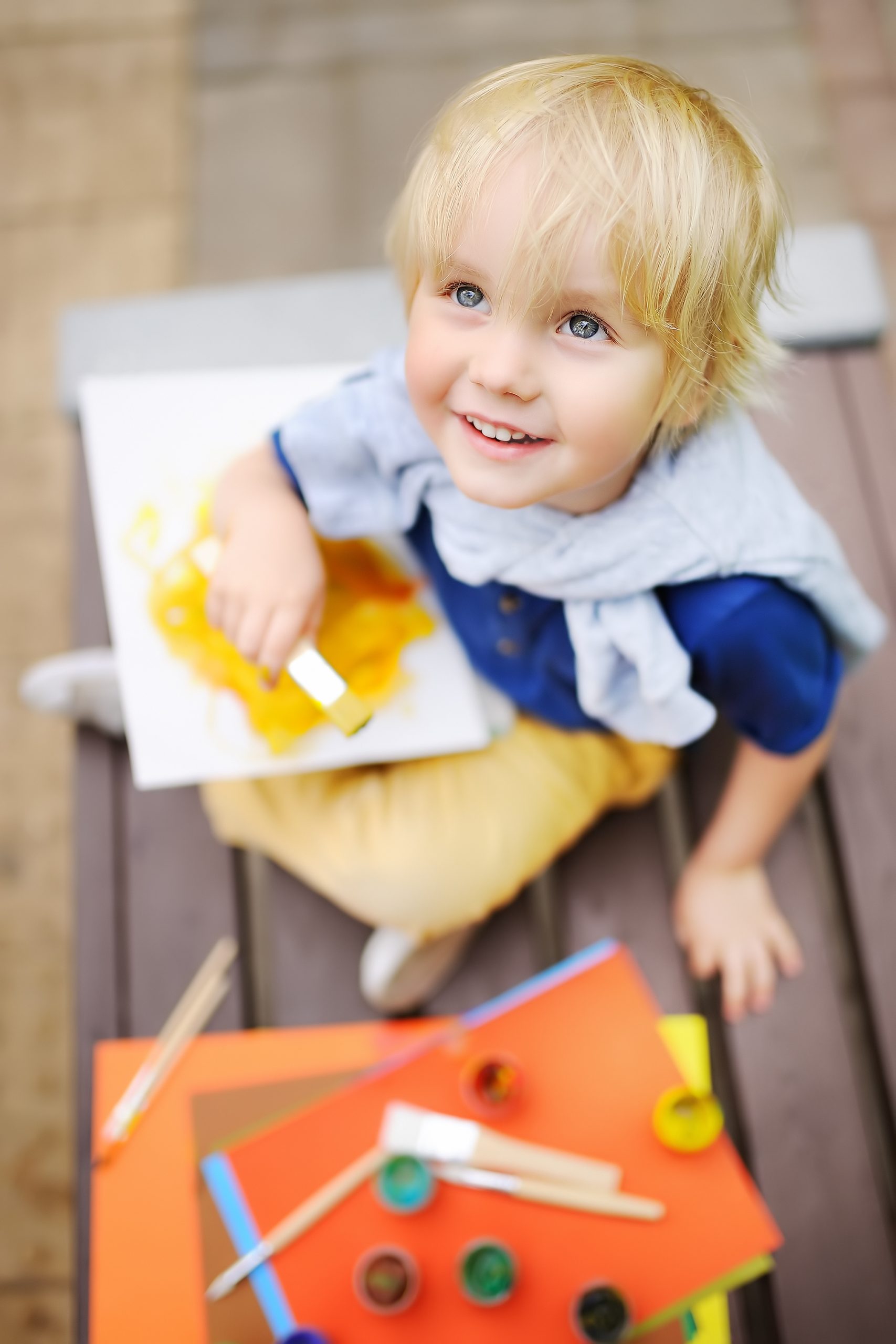 Cute little boy drawing with colorful paints in fall park