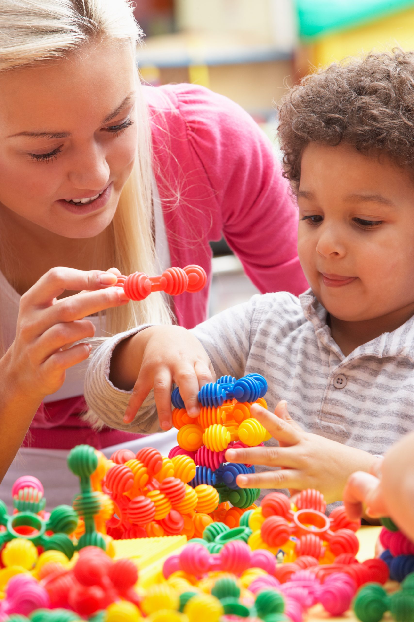 Young woman playing with a boy by stacking toys on top of each other